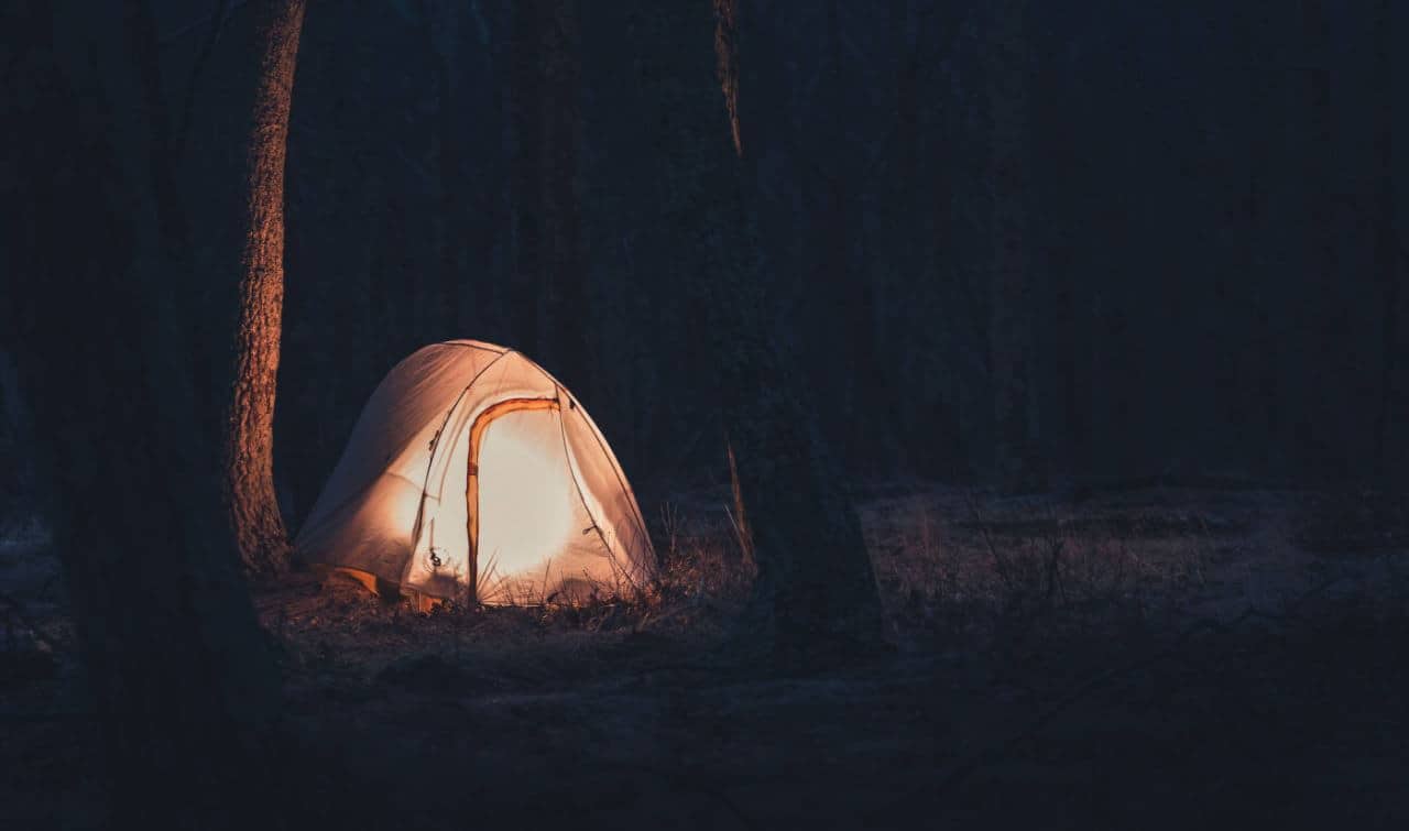 A lit camping tent in the forest