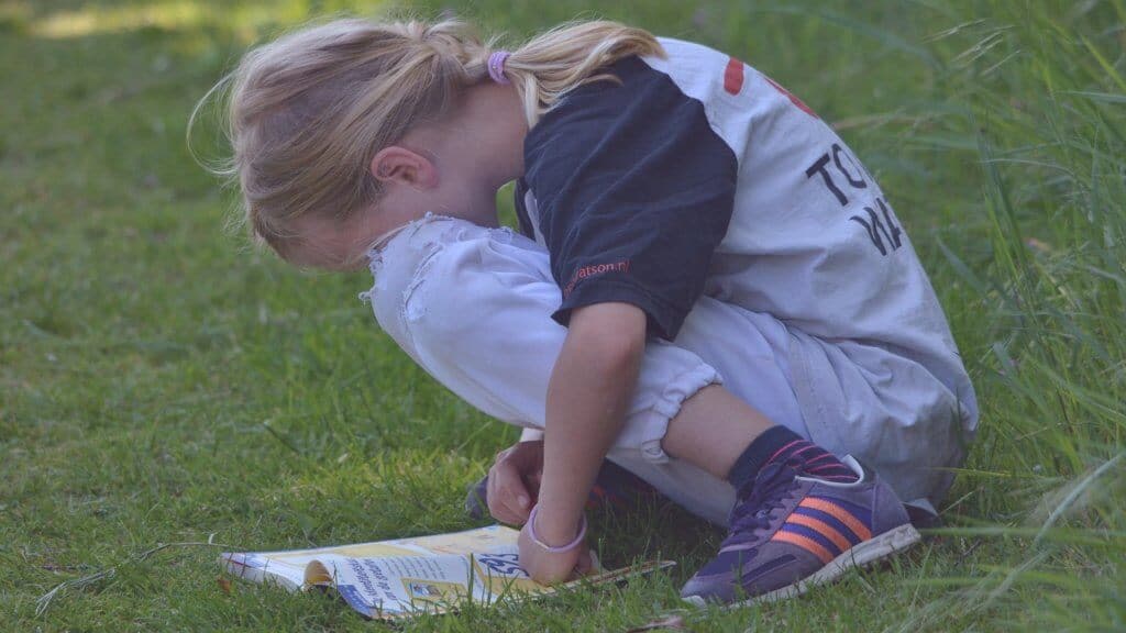 Young girl crouching down to read a magazine