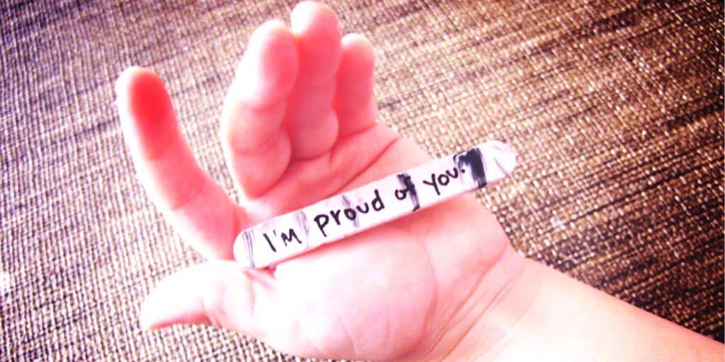 Hand holding a note that says "I'm proud of You"