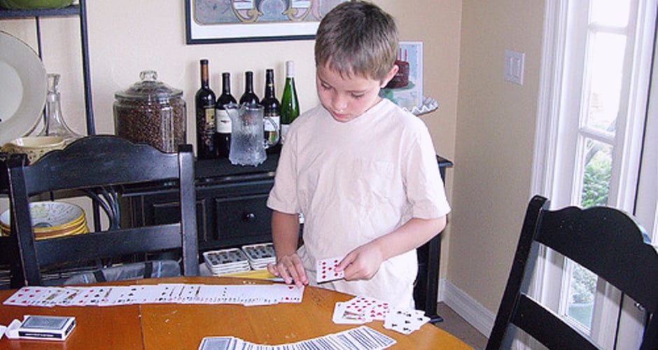 A child learning a magic trick with a deck of cards