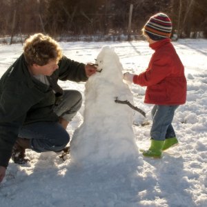 Father and son building a snowman outside