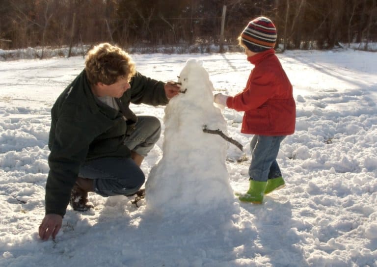 Father and son building a snowman outside