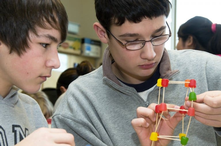 Middle school students piece together a bridge they've designed using toothpicks and gumdrops.