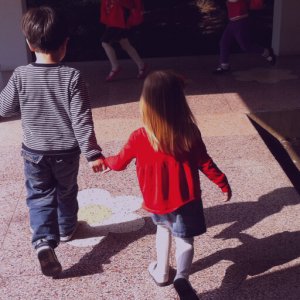 Two siblings running together holding hands